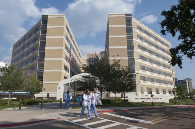 People crossing the street in front of University Hospital.